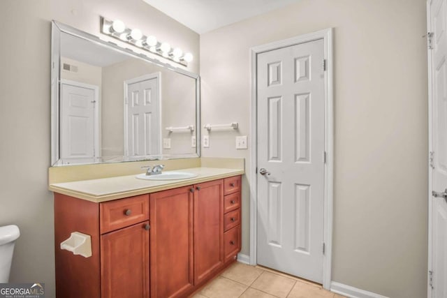 bathroom with toilet, vanity, and tile patterned floors