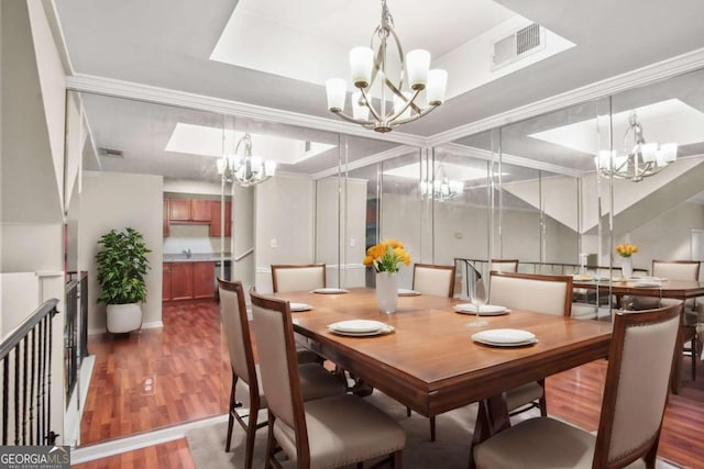 dining space with sink, crown molding, dark wood-type flooring, and a notable chandelier