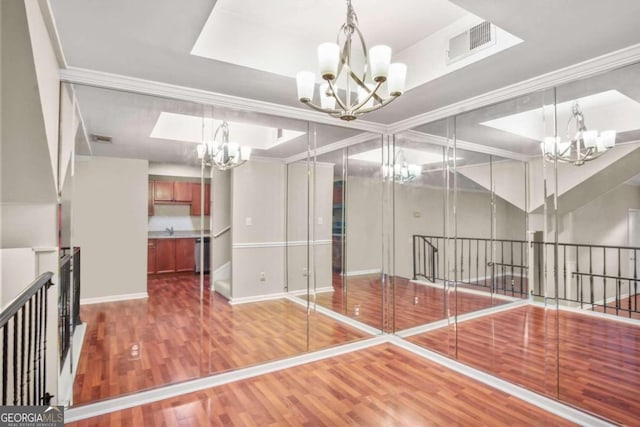 exercise area featuring hardwood / wood-style floors, ornamental molding, and a notable chandelier