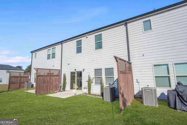 rear view of house featuring central AC unit and a lawn