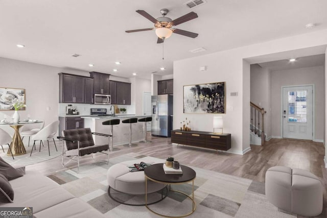 living room with light hardwood / wood-style flooring and ceiling fan