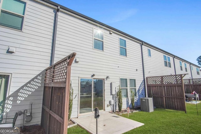 rear view of house featuring a yard, central AC unit, and a patio area