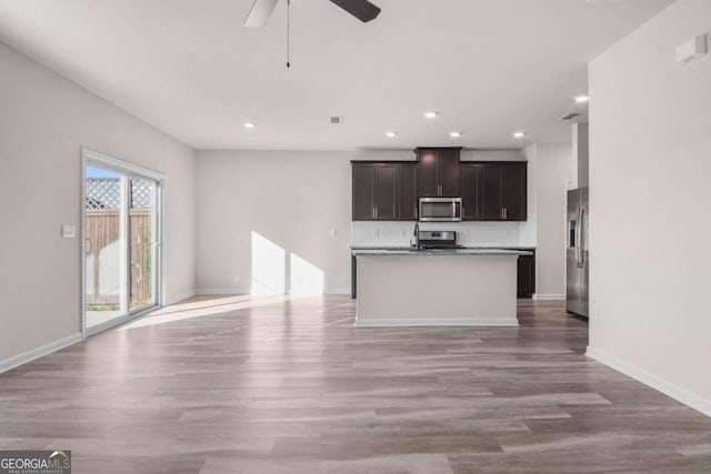 kitchen with dark brown cabinetry, ceiling fan, light hardwood / wood-style floors, a kitchen island with sink, and appliances with stainless steel finishes