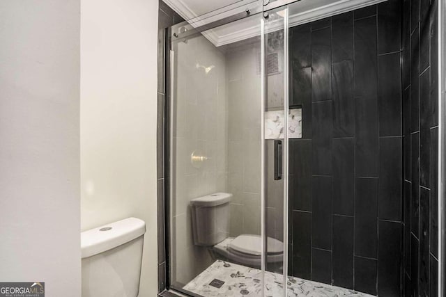 bathroom with toilet, a shower with shower door, and ornamental molding