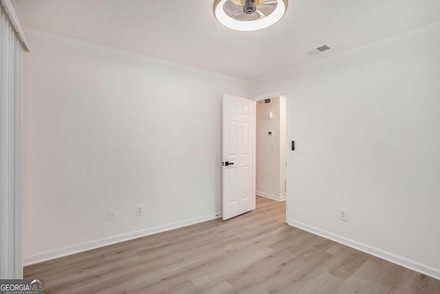 unfurnished room with ornamental molding and light wood-type flooring