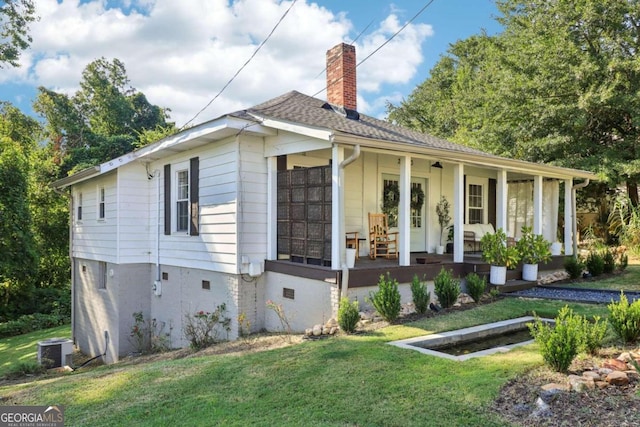 view of front of property with cooling unit, covered porch, and a front yard