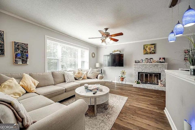 living room with a textured ceiling, ceiling fan, dark wood-type flooring, and a brick fireplace