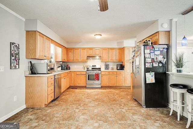 kitchen featuring sink, pendant lighting, a textured ceiling, light brown cabinetry, and appliances with stainless steel finishes