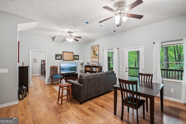 living room with ceiling fan, light hardwood / wood-style floors, and a textured ceiling