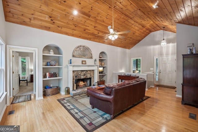 living room featuring wood ceiling, built in shelves, ceiling fan, light hardwood / wood-style flooring, and a fireplace