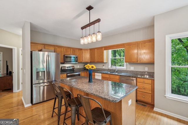 kitchen with light wood-type flooring, a center island, stainless steel appliances, and sink