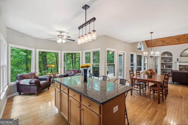 kitchen featuring dark stone counters, pendant lighting, a healthy amount of sunlight, and light hardwood / wood-style floors