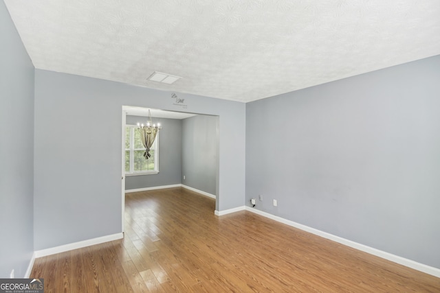 spare room featuring hardwood / wood-style flooring, a textured ceiling, and a chandelier