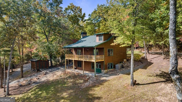 rear view of property featuring a storage shed, central air condition unit, and a deck