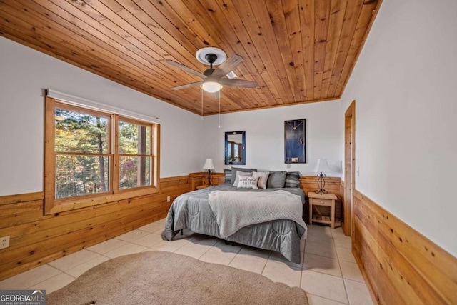 tiled bedroom featuring ceiling fan, wooden ceiling, and wooden walls