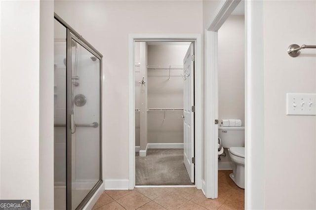 bathroom with tile patterned flooring, a shower with shower door, and toilet