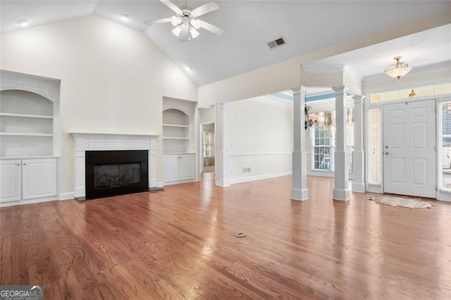 unfurnished living room with ceiling fan with notable chandelier, hardwood / wood-style flooring, built in features, and lofted ceiling