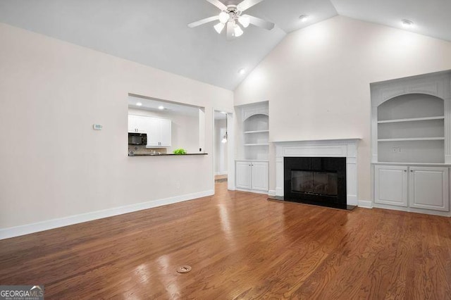 unfurnished living room with hardwood / wood-style floors, high vaulted ceiling, built in features, and ceiling fan