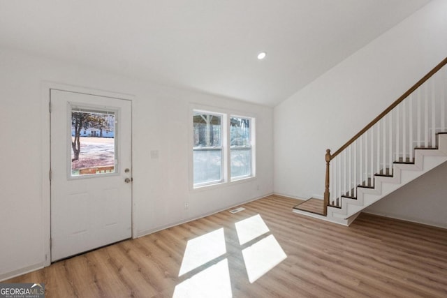 entrance foyer with a healthy amount of sunlight, vaulted ceiling, and light hardwood / wood-style flooring