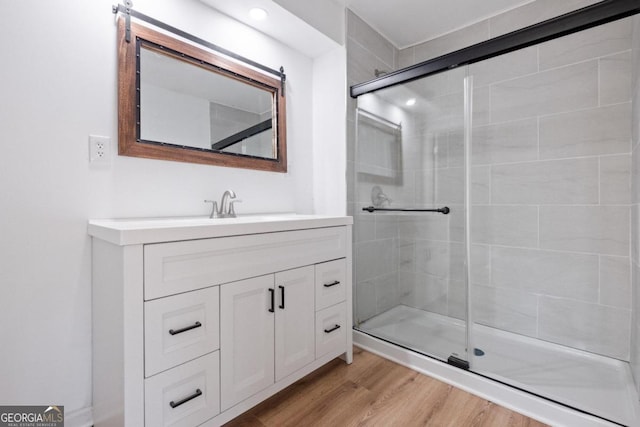 bathroom featuring hardwood / wood-style flooring, vanity, and walk in shower