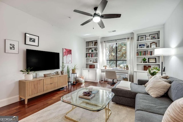 living room with hardwood / wood-style floors, built in features, and ceiling fan