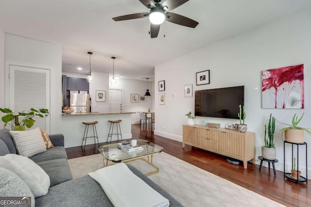 living room featuring ceiling fan and dark hardwood / wood-style flooring