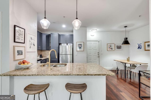 kitchen with a kitchen bar, kitchen peninsula, stainless steel fridge, and decorative light fixtures