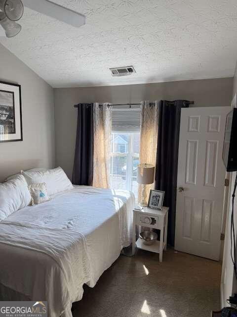 bedroom with carpet flooring, lofted ceiling, and a textured ceiling