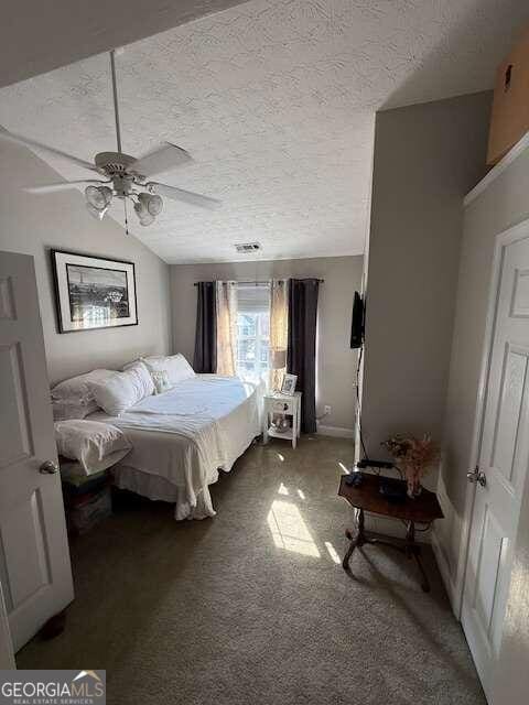 carpeted bedroom with a textured ceiling, ceiling fan, and lofted ceiling