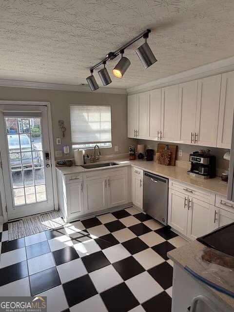 kitchen featuring track lighting, sink, stainless steel dishwasher, a textured ceiling, and white cabinetry