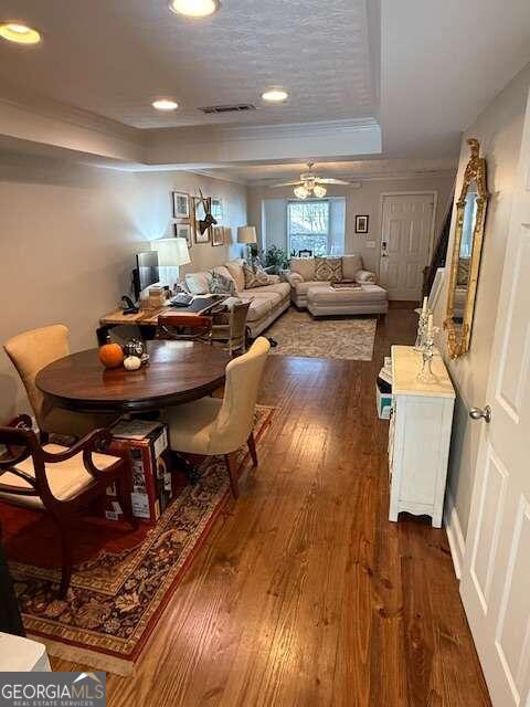 dining room featuring ceiling fan, crown molding, dark wood-type flooring, and a tray ceiling