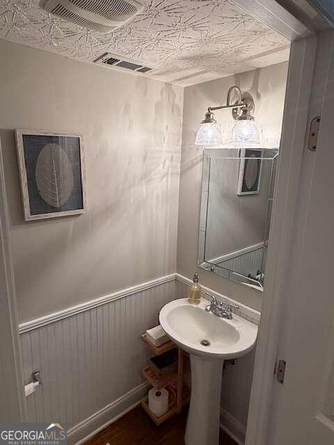 bathroom with hardwood / wood-style floors and wooden walls