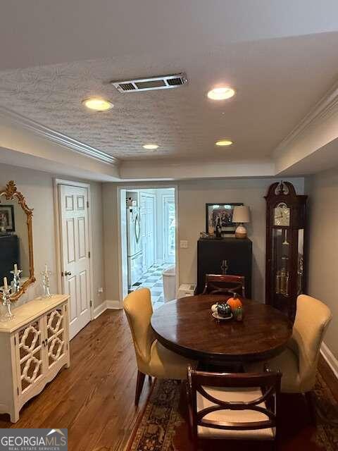 dining area featuring dark hardwood / wood-style flooring, ornamental molding, and a tray ceiling