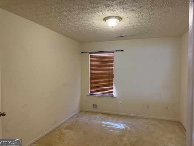 carpeted empty room featuring a textured ceiling