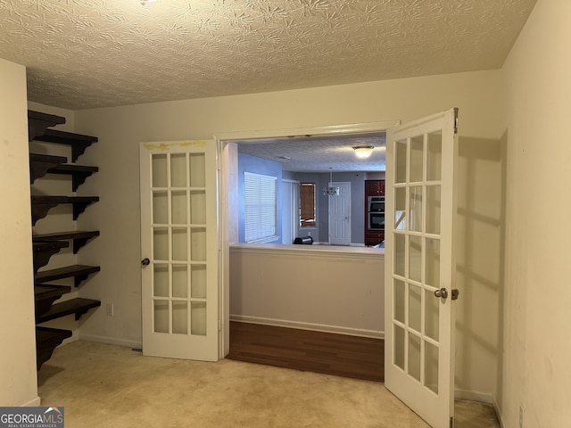 spare room with french doors, light colored carpet, and a textured ceiling