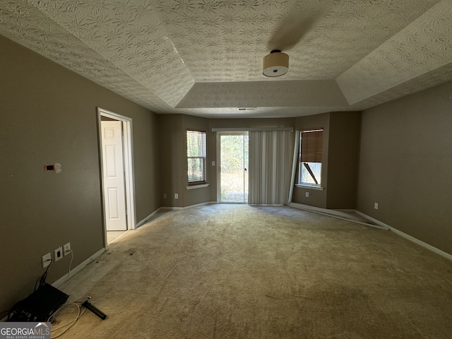 unfurnished room with carpet flooring, a raised ceiling, and a textured ceiling