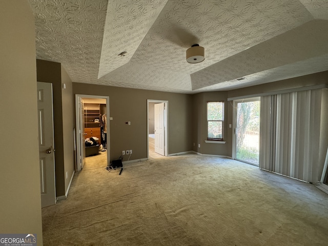 unfurnished bedroom with a textured ceiling, access to outside, light colored carpet, a spacious closet, and a closet