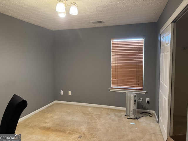 carpeted empty room featuring radiator heating unit, a textured ceiling, and a chandelier