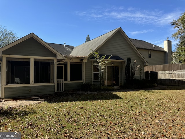 back of house featuring a lawn and a sunroom