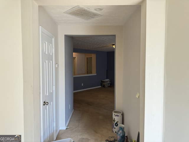 corridor featuring light colored carpet and a textured ceiling