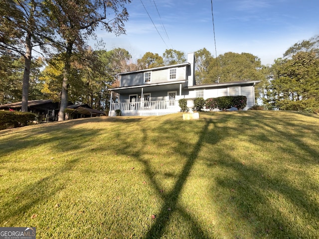 rear view of house featuring a yard and a porch