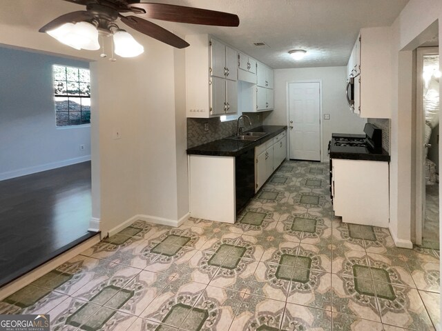 kitchen with backsplash, white range oven, ceiling fan, sink, and white cabinetry