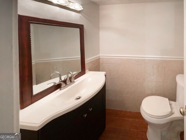 bathroom featuring tile patterned flooring, vanity, tile walls, and toilet