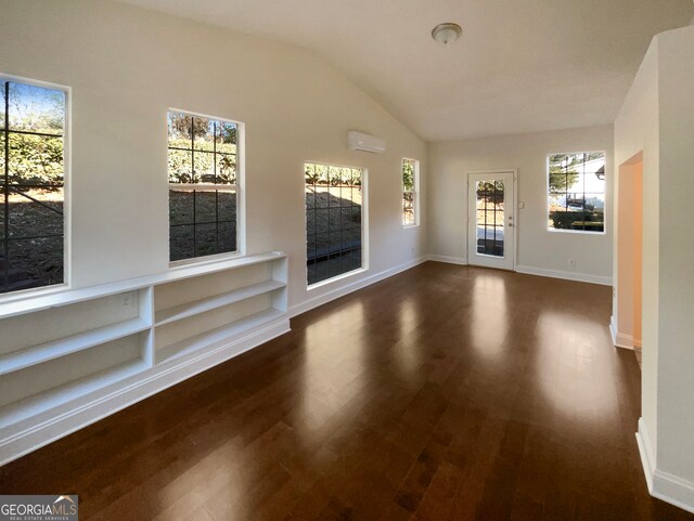 unfurnished living room with a wall unit AC, a wealth of natural light, and dark hardwood / wood-style flooring