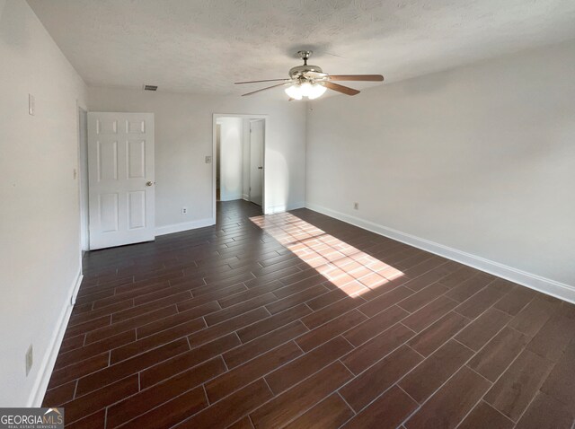 unfurnished room featuring ceiling fan, dark hardwood / wood-style flooring, and a textured ceiling