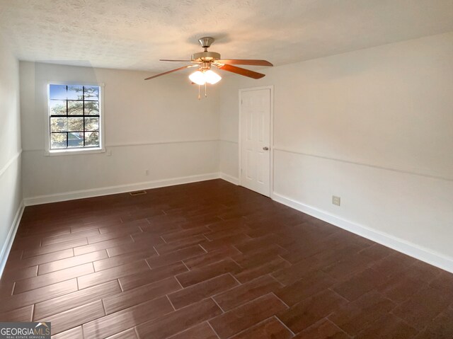 unfurnished room featuring a textured ceiling, ceiling fan, and dark wood-type flooring