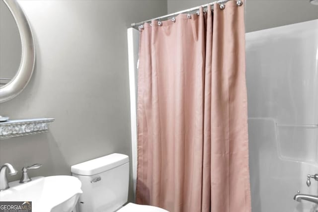 bathroom featuring a shower with shower curtain, toilet, and sink