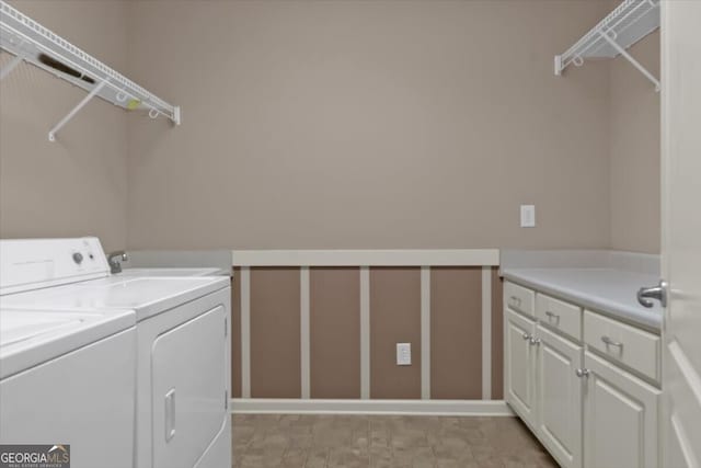 clothes washing area featuring cabinets and washer and clothes dryer