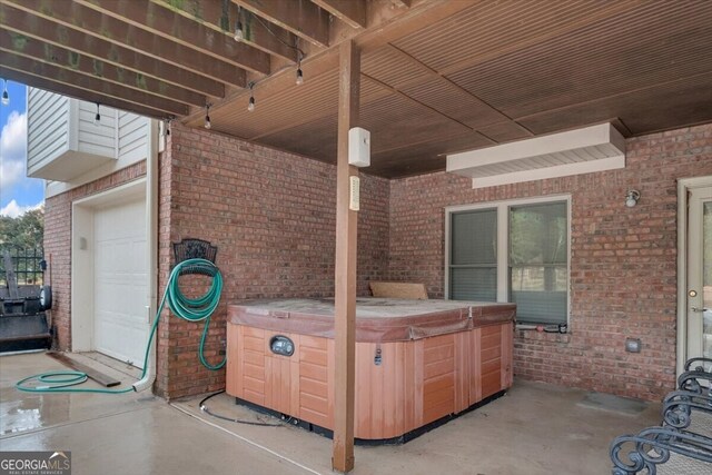 view of patio featuring a hot tub and a garage