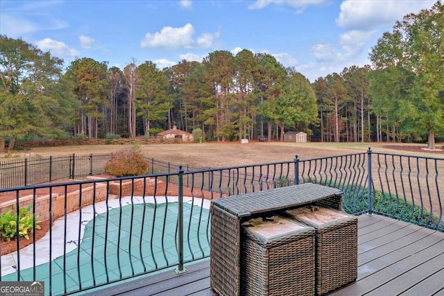 wooden deck with a fenced in pool and a shed